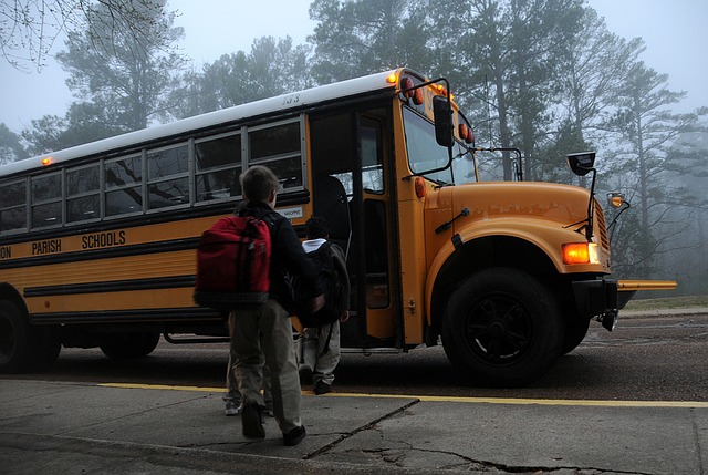 Child boarding a school bus with heavy backpack